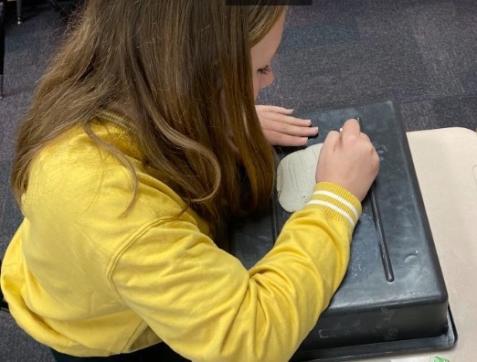 A student writes on clay